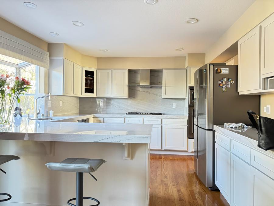 Finished kitchen with warm white cabinets, stone backsplash and countertops