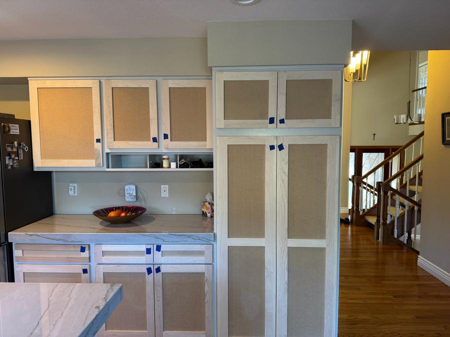 Kitchen cabinets mid-refinish with raw sanded wood doors