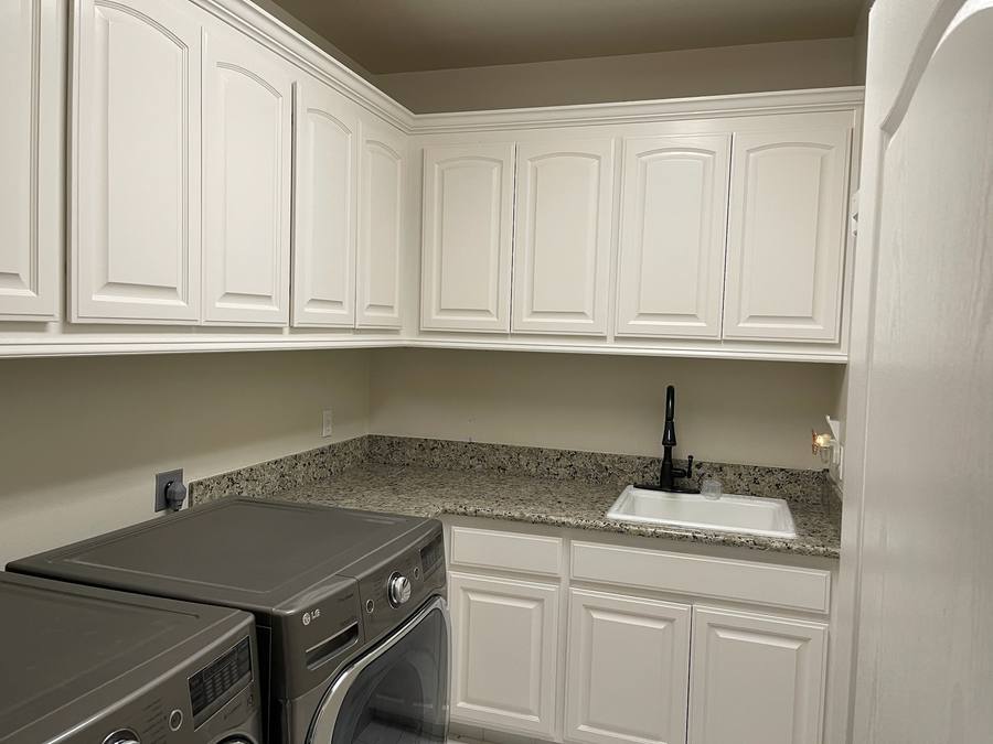 Laundry room with bright white cabinets after refinishing